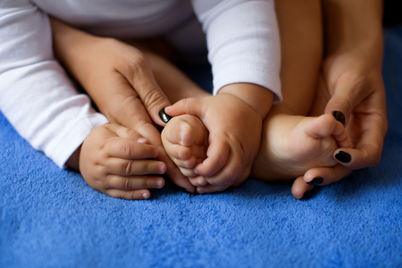 Hands of mother in the form of a heart on children's legsの写真素材