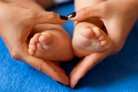 Hands of mother in the form of a heart on children's legsの写真素材