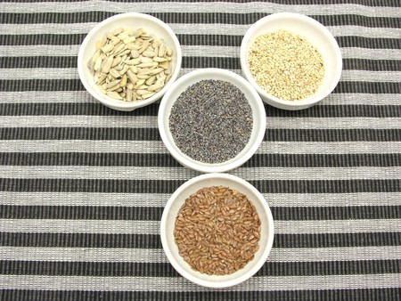 Four bowl with different seeds on a striped backgroundの写真素材