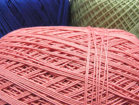 Three balls of wool  in blue, pink and green in a close-up view