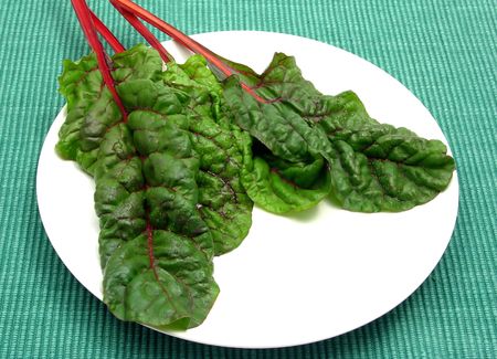 Four red stemmed chard leaves on white plate