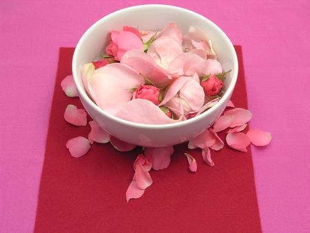 Pink roses in a white bowl of chinaware on red backgroundの写真素材