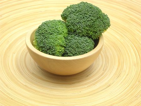 Wooden bowl with broccoli on bamboo plateの写真素材