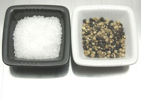 Bowls of chinaware with salt and pepper on reflecting mattingの写真素材
