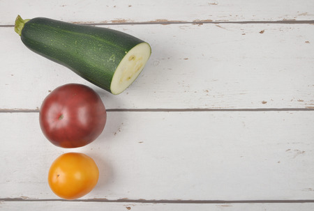 Tomatoes and zucchini on weatered plankの写真素材