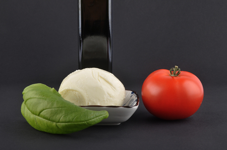 Mozzarella, basil, olive oil and tomato on blackの写真素材