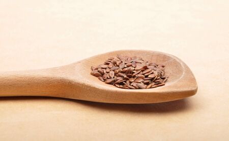 Linseed on wooden spoon and brown backgroundの写真素材