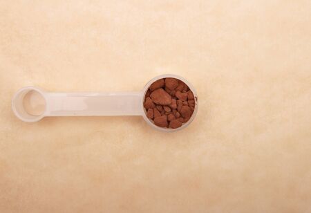 Cacao powder in measuring spoon on brown backgroundの写真素材