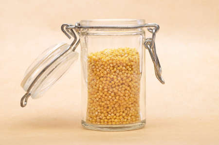 Raw millet in jar and on brown backgroundの写真素材