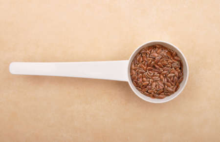 Linseed in measuring spoon on brown backgroundの写真素材