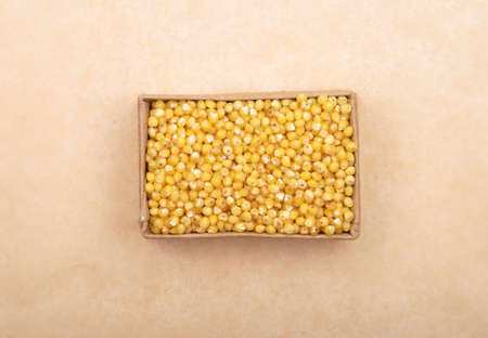 Raw millet in carton and on brown backgroundの写真素材