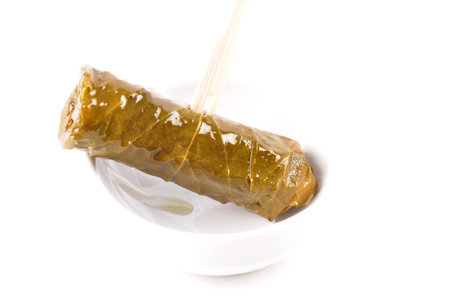 Stuffed vine leaves on wooden skewers and porcelain bowl on white backgroundの写真素材