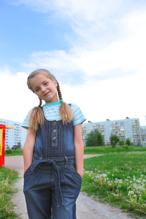 cute little girl in jeans overalls outdoorsの写真素材