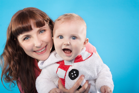 pretty young mother with the cute little baby on the blue backgroundの写真素材