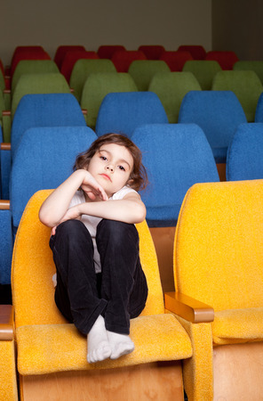 cute pretty little girl sitting in the cinema hallの写真素材