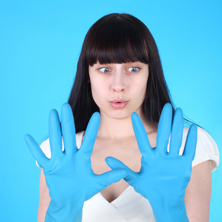 pretty girl in the festive dress looking surprised at her rubber household glovesの写真素材