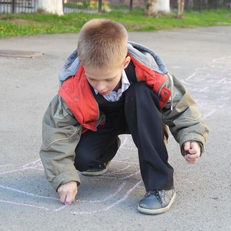 little boy drawing with color chalksの写真素材
