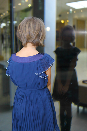 pretty little girl looking at her window reflectionの写真素材