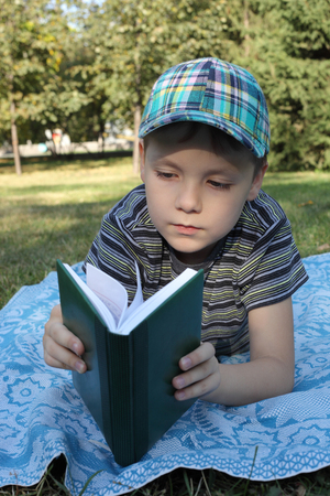 cute little boy reading a book outdoorsの写真素材