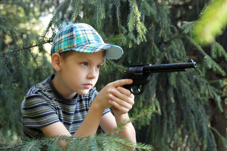 cute little boy with the gun playing in a parkの写真素材