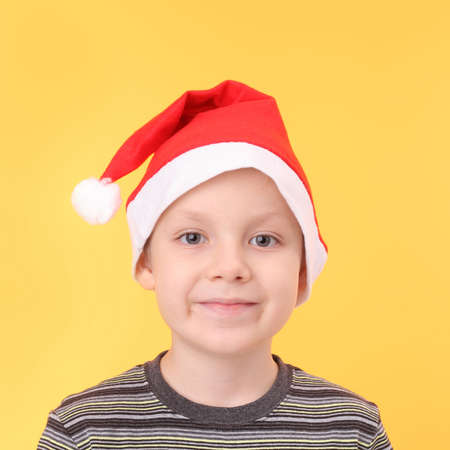 Little boy in Santa Claus cap on the yellow backgroundの写真素材