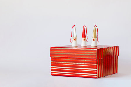 three Santa Clauses figures on a red striped gift box, white background, side view, copy spaceの写真素材