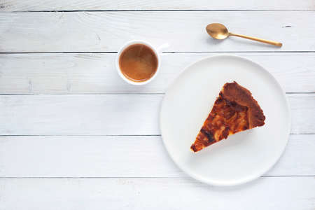 slice of onion pie on a plate, cup of coffee and spoon on the white wooden background, top view, copy spaceの写真素材