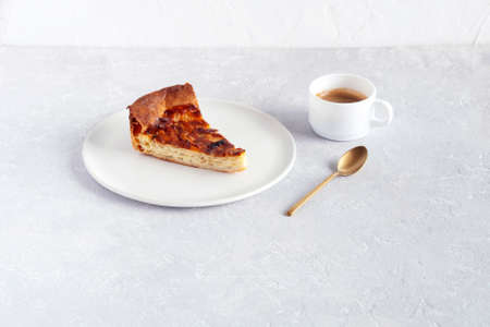 slice of onion pie on a plate, cup of coffee and spoon on the gray background, side viewの写真素材
