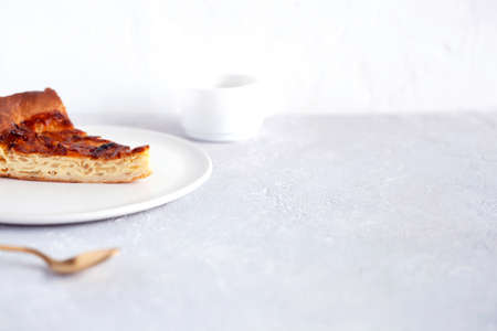 slice of onion pie on a plate, cup of coffee and spoon on the gray background, side view, copy spaceの写真素材