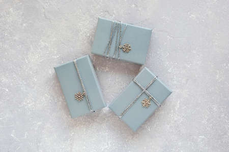 gray christmas gift boxes decorated with silver metal snowflakes on the gray concrete background, top viewの写真素材