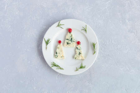 new year trees made of roquefort cheese and decorated with red currants, on a plate, gray background, top viewの写真素材