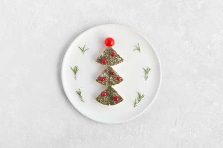 new year tree made of cheese and decorated with red currant and cherry tomatoes, decoration for new year table, white plate, top viewの写真素材