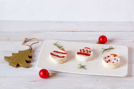 new year appetizer made of round cheese and pepper berries, white wooden background, side viewの写真素材