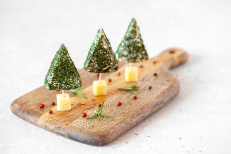appetizer of new year trees made of cheese and decorated with dill, easy cooking, on the wooden cutting board, side viewの写真素材