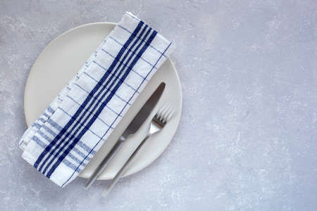 matte plates and cutlery on the gray background, top view, copy space
