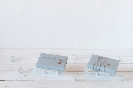 tiny decorative sleds with gray Christmas gift boxes, white, gray and silver colors, copy space, idea for Christmas cardの写真素材