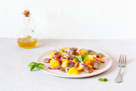 smoked herring, potatoes and red onion salad on a plate, concept of fresh food, side viewの写真素材