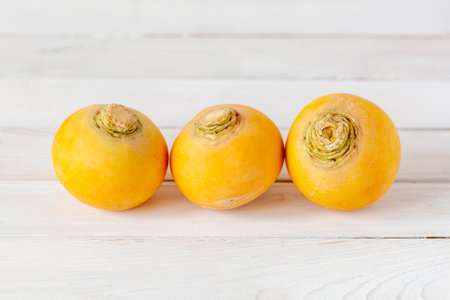 Three bright yellow turnips on white wooden backgroundの写真素材