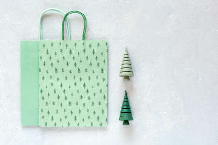 green paper Christmas tree pattern bags and wooden Christmas trees on gray background, top view, copy spaceの写真素材