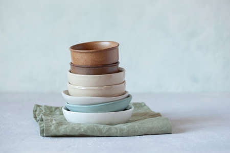 stack of ceramic and sandstone empty bowls of natural colors on green textile linen napkinの写真素材