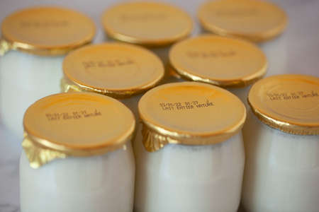 natural whole milk industrial yogurt in glass pots with the expiration dateの写真素材
