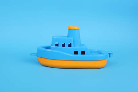 blue and yellow plastic toy boat on blue backgroundの写真素材