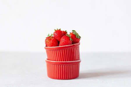 fresh organic strawberries in a red bowl, white background, side viewの写真素材