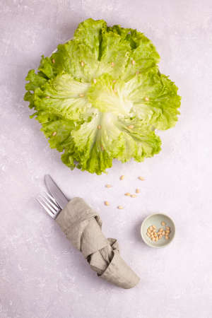 green salad on a plate served with pine nuts, minimalism concept, cutlery covered with a napkin, vertical photo, top viewの写真素材