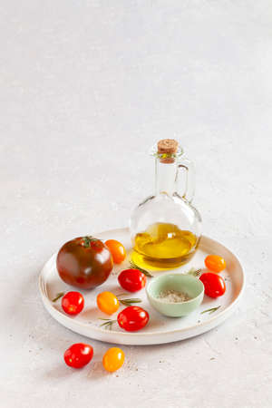 round tray with different tomato varieties, served with salt and olive oil, side view, copy spaceの写真素材