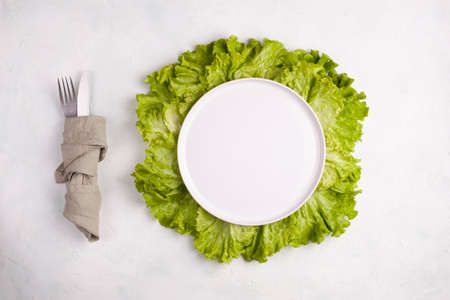 empty white round plate on the green salad leaves, healthy eating conceptの写真素材