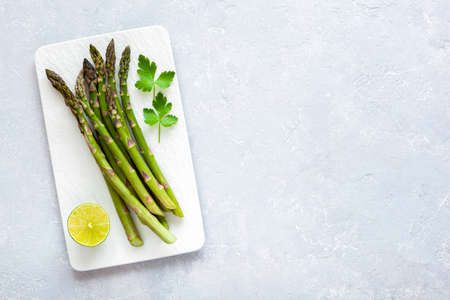 Asparagus stems on the rectangular plate served with green lemon and parsleyの写真素材