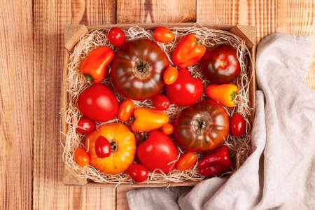 Tomatoes of different varieties in a wooden case on the wooden backgroundの写真素材