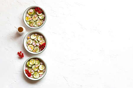 Radish and cucumber salad served in a three small round bowls in a rowの写真素材