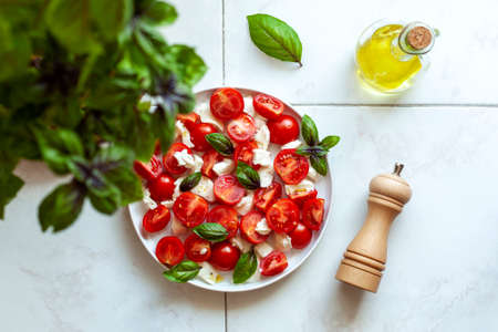 Portion of caprese salad under basil plantの写真素材